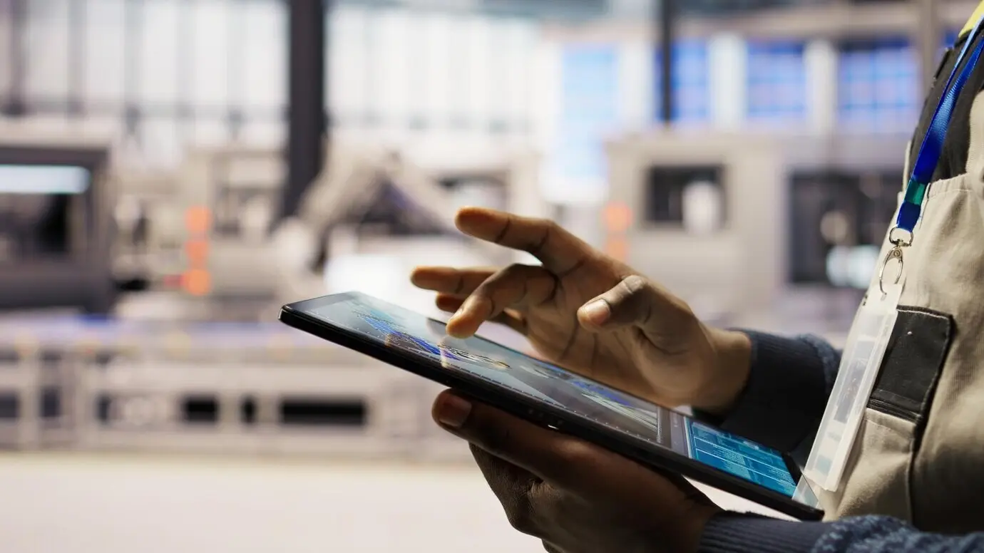 Primer plano de un ingeniero usando una tableta para diseñar planos de planta de una fábrica de paneles solares.